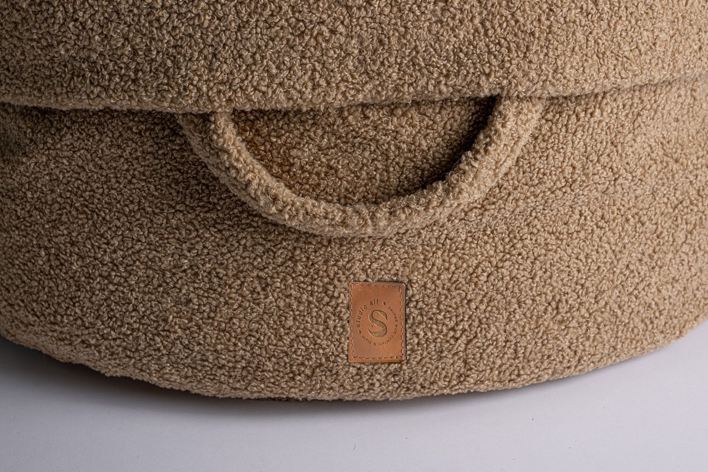 Detail van het Studio Sif leren label en teddy handvat van de Pooch Pouch Teddy Cookie hondenmand in beige-bruin