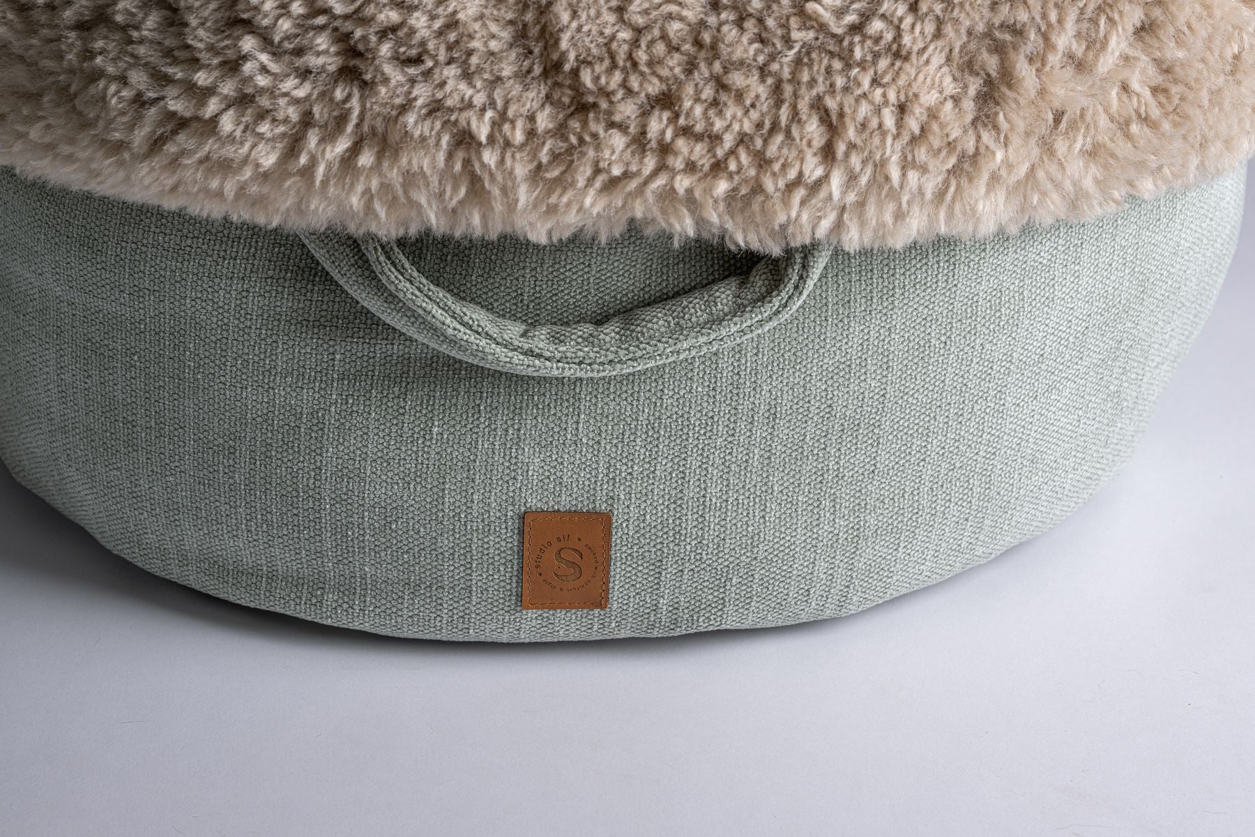 Detail van ronde hondenmand, handvat en bontrand en luxe duurzame stof in de kleur mint